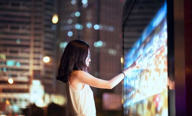 Woman touching screen display in the city