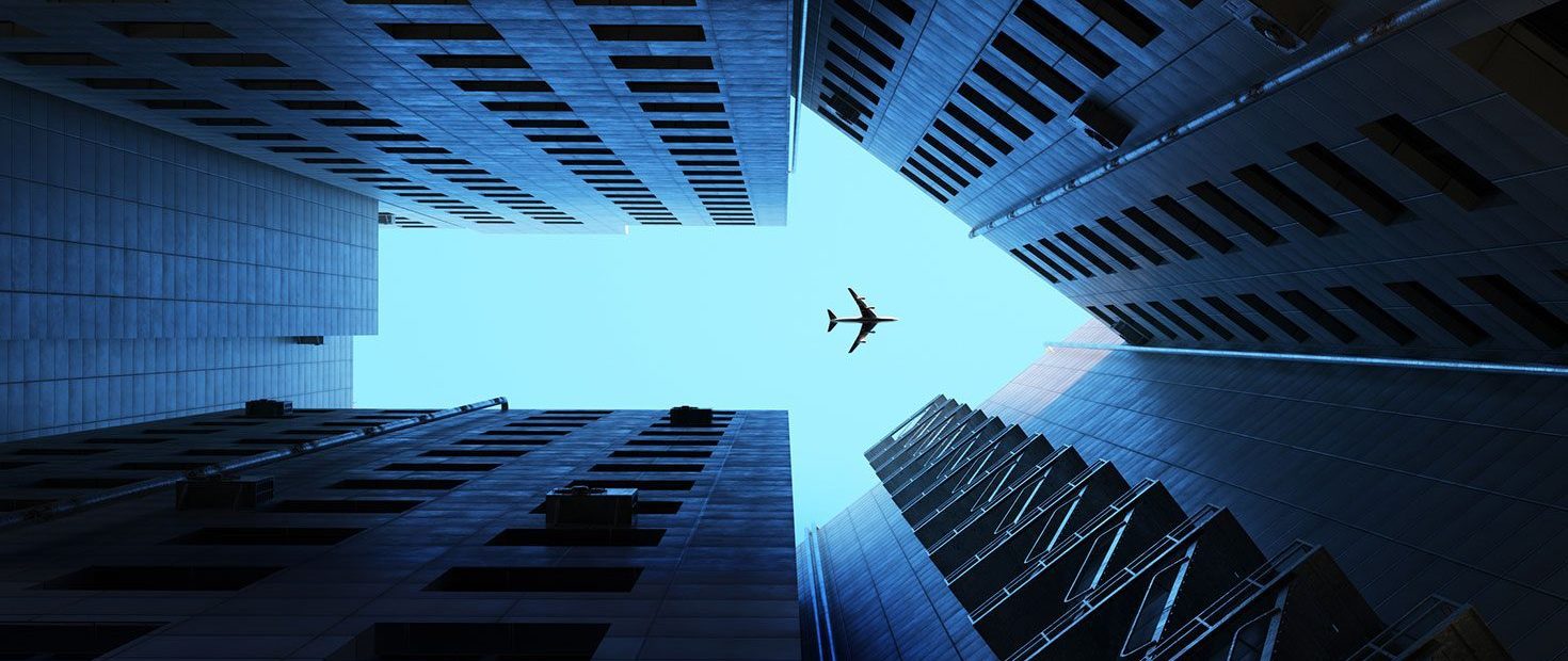 Airplane flying on blue sky, above buildings