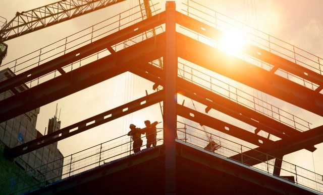Construction workers silhouetted against the sun