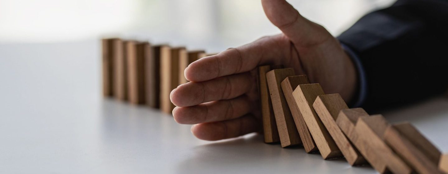 Businessman prevents wooden blocks from falling with his hands