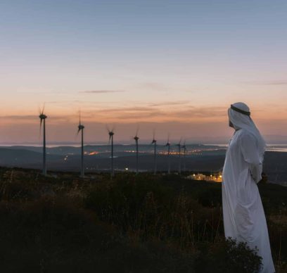 Middle Eastern Businessman in wind turbine farm at sunset