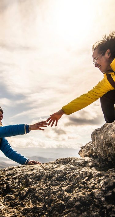 People helping each other hike up a mountain