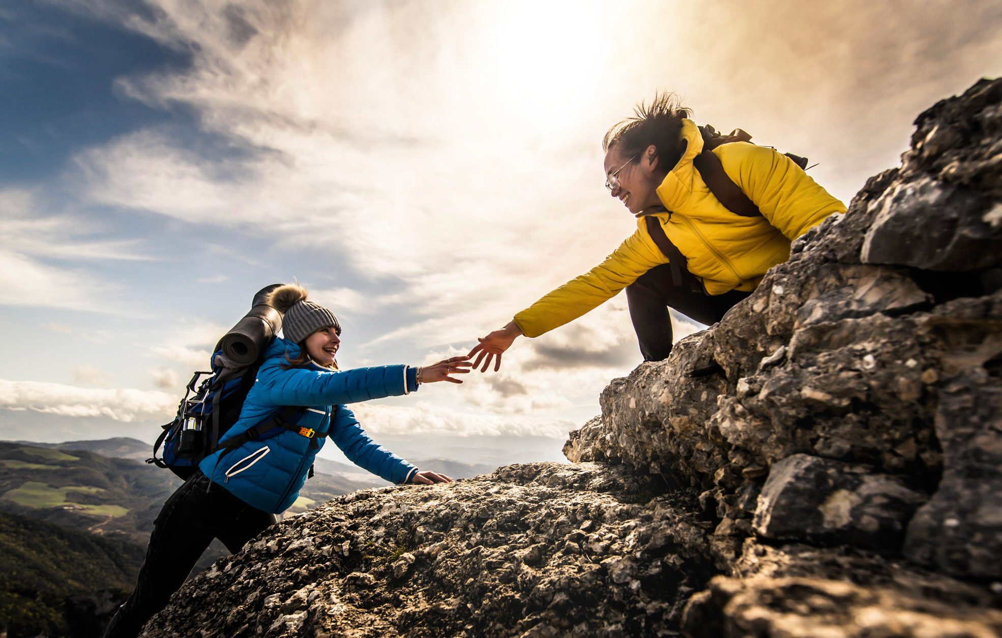 People helping each other hike up a mountain