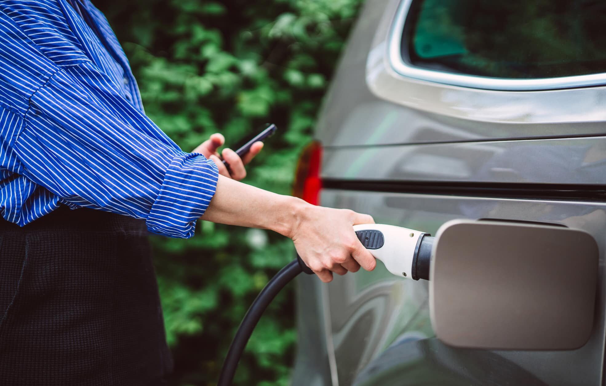 Woman charging her electric car at EV charging station