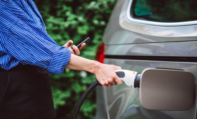 Woman charging her electric car at EV charging station