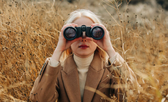 Business woman looking through binoculars